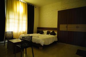 een slaapkamer met een bed en een tafel en stoelen bij Meridian Rooms and Service Apartment in Mysore