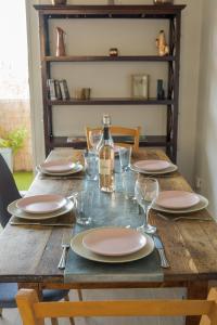 - une table en bois avec des assiettes, des verres et une bouteille de vin dans l'établissement Le Casselardit -T4 proche Hôpital - Clim - Balcon, à Toulouse