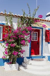 una porta rossa e fiori rosa di fronte a una casa di Casa Vó Briata a Mértola