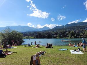 a group of people sitting on the grass near a lake at L'AvantGardiste, Spacious 6 bedroom panoramic view in Crans-Montana