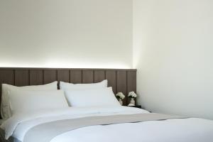 1 cama grande con sábanas y almohadas blancas en The Hotel Sokcho by Best Western Signature Collection, en Sokcho