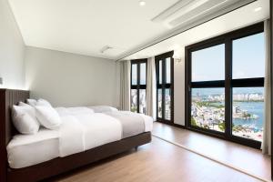 1 dormitorio con cama blanca y ventanas grandes en The Hotel Sokcho by Best Western Signature Collection, en Sokcho