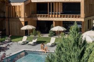 una mujer sentada junto a una piscina en Dolmites Nature Hotel Vigilerhof, en Siusi