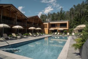 un hotel con una piscina con sillas y sombrillas en Dolmites Nature Hotel Vigilerhof, en Siusi