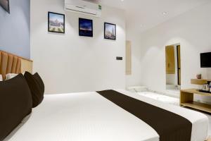 1 dormitorio con cama blanca y cuadros en la pared en Hotel O World View, en Surat