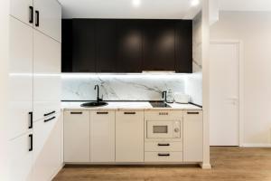 a white kitchen with black cabinets and a sink at Solridge Aparthotel in Tbilisi City