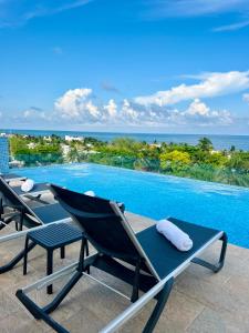 a view of a swimming pool with two lawn chairs at Areia Boutique Hotel - Puerto Morelos in Puerto Morelos