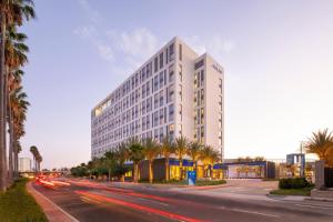 安纳海姆The Viv Hotel, Anaheim, a Tribute Portfolio Hotel的一条棕榈树街道上的高大的白色建筑