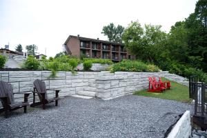 einen Garten mit zwei Stühlen und einer Steinmauer in der Unterkunft Ramada by Wyndham Ottawa On The Rideau in Ottawa