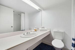 Baño blanco con lavabo y aseo en Econo Lodge Dockside Glenelg, en Adelaida