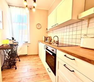 cocina con armarios blancos, fregadero y mesa en Herzraum Appartement,kostenfreier Parkplatz,Innenstadt Babybett,Familie u Buisness,gratis Kaffee und Tee, en Bautzen