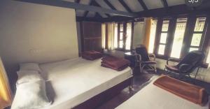 a bedroom with a bed and two chairs and windows at Saaranga homestay in Avathi