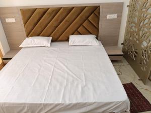 a large white bed with two pillows on it at Aarohi studio hotels in Noida