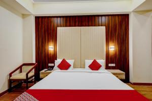 1 dormitorio con 1 cama blanca grande con almohadas rojas en Hotel O SAI GRAND LUXURY ROOMS, en Tirupati