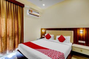 1 dormitorio con 1 cama grande con almohadas rojas en Hotel O SAI GRAND LUXURY ROOMS, en Tirupati