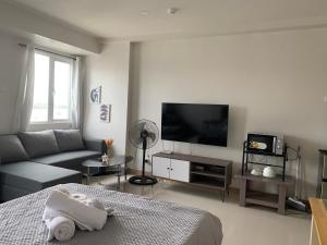 uma sala de estar com um sofá e uma televisão de ecrã plano em Style Residences-Cozie Stays em Iloilo