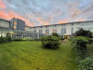 un grand bâtiment avec une pelouse devant lui dans l'établissement Mercure Hotel Gera City, à Gera