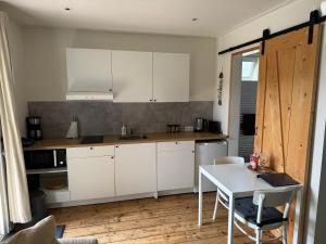 cocina con armarios blancos y mesa en Studio appartement 1nul9Noord, en Renesse