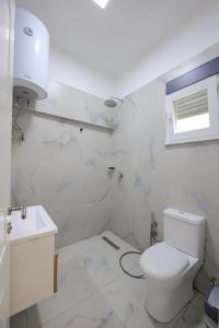 een witte badkamer met een toilet en een wastafel bij Domi Beach Valley in Dhërmi