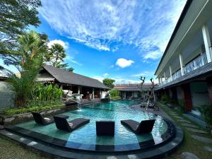 una piscina con tumbonas frente a un edificio en Puri Andong Villa, en Ubud