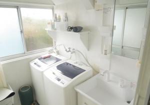 een witte badkamer met een wasmachine en een wastafel bij Kairakuen Guesthouse - Vacation STAY 26929v in Mito