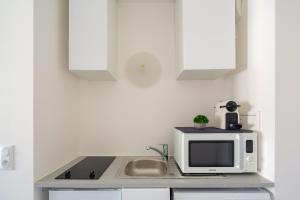 a kitchen with a microwave and a sink at Le Péruvien - Saint-Cyr-L'Ecole - Free Parking in Saint-Cyr-lʼÉcole