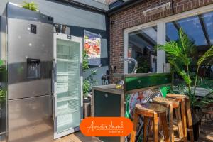 an outdoor kitchen with a refrigerator and stools at 10 min to Amsterdam! 26 beds, Jacuzzi's, & Disco! in Zwanenburg