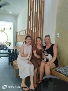 trois femmes assises sur un banc avec un chien dans l'établissement Hue Sweethouse 2 Homestay, à Hue