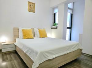 een witte slaapkamer met een groot bed met gele kussens bij VR2 Central Apartment in Boekarest