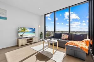 uma sala de estar com um sofá e uma televisão em Skygarden On The Glen em Glen Waverley