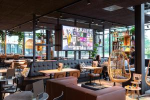 Moxy Amsterdam Schiphol Airport في هوفدوربْ: مطعم بطاولات وكراسي وشاشة كبيرة