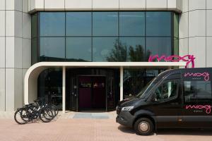 Moxy Amsterdam Schiphol Airport في هوفدوربْ: سيارة فان سوداء متوقفة أمام مبنى مع الدراجات