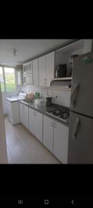 a kitchen with white cabinets and a refrigerator at Apartamento hogareño in Pereira