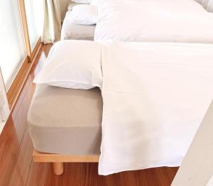 - 2 lits avec des draps blancs au-dessus d'une table en bois dans l'établissement かぐら庵, à Kitakata