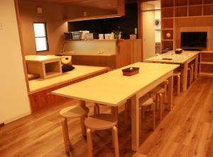 - une cuisine avec des tables et des tabourets en bois dans l'établissement Hostel OSAKA, à Osaka