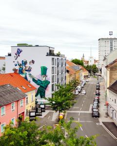 een stadsstraat met een muurschildering aan de zijkant van een gebouw bij Lendhotel in Graz