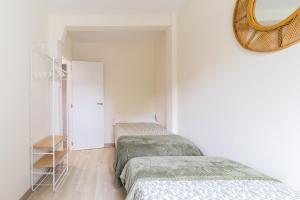 2 bedden in een witte kamer met een spiegel bij Precioso apartamento en el centro recién reformado in Santander