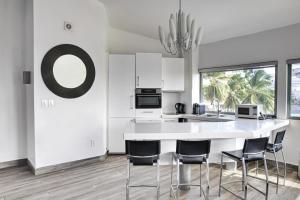 a white kitchen with a large white table and chairs at Commodore Suites in Simpson Bay