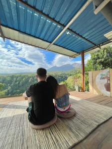 a man and woman sitting on a deck looking at the view at Rinjani Houseboon in Senaru