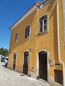 un edificio amarillo al lado de una calle en Dom Camilo Alojamento local, en Minde