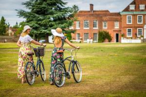 dos mujeres de pie con bicicletas delante de un edificio en Stoke Place- Part of the Cairn Collection, en Slough