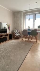 een woonkamer met een tv en een tafel en stoelen bij Kaktusik in Suwałki