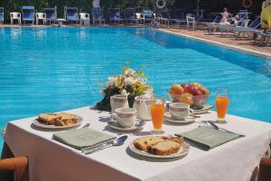 een tafel met eten en fruit naast een zwembad bij Hotel Giordano in Ravello