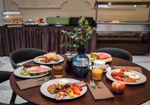 een tafel met borden eten en drinken erop bij Hotel Maestro by Adrez in Praag