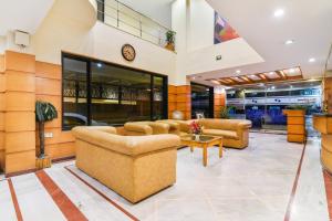 a lobby with couches and a clock on the wall at Capital O Grand Plaza in Coimbatore