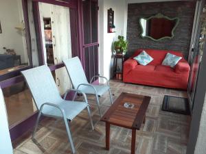 een woonkamer met 2 stoelen en een rode bank bij Apartamento en Atlántida, A una cuadra de la Playa y 2 calles del Centro Excelente ubicación in Atlántida