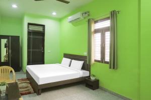 a bedroom with a white bed and green walls at Capital O A-one in Manesar