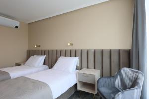 a hotel room with two beds and a chair at Suncity Hotel & SPA in Šiauliai