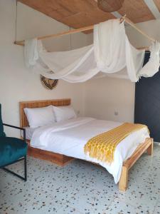 ein Schlafzimmer mit einem Himmelbett und einem Stuhl in der Unterkunft Thatched Cottage Suites in Jinja