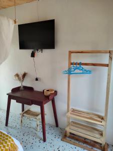 Zimmer mit einem Schreibtisch und einem TV an der Wand in der Unterkunft Thatched Cottage Suites in Jinja